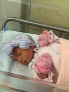 Newborn baby girl in a bassinet with a cap 