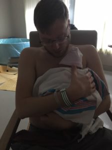Father holding newborn skin to skin