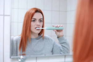 Red haired woman brushig her teeth