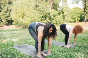 2 pregnant women doing prenatal yoga in a park 