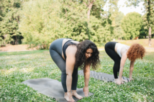 2 pregnant women doing prenatal yoga in a park