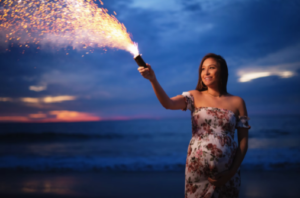 Pregnant woman in a floral dress holding out a sparkler