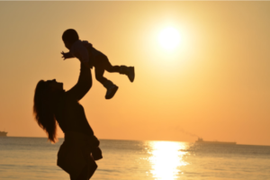 woman tossing baby in the air against a sunset