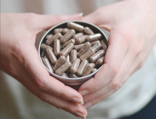 2 hands holding a tin of placenta encapsulation pils