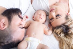 Blonde woman, man with a beard in a bed with a baby in a diaper