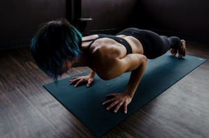 woman with blue and black hair doing a plank