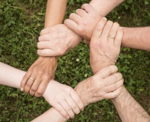 6 assorted hands holding each others wrist making a pentagon shape