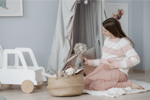 Brunnete woman is peach dress setting up a newborn nursery