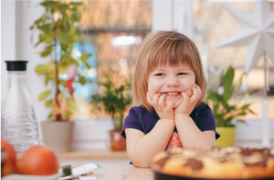 a toddler sitting at a set table smiling