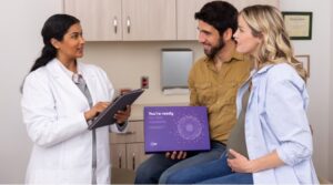 Dark skinned female doctor speaking with a blonde woman and brunet bearded male