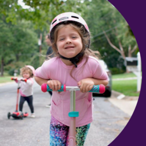 A child wearing a helmet and riding a scooter