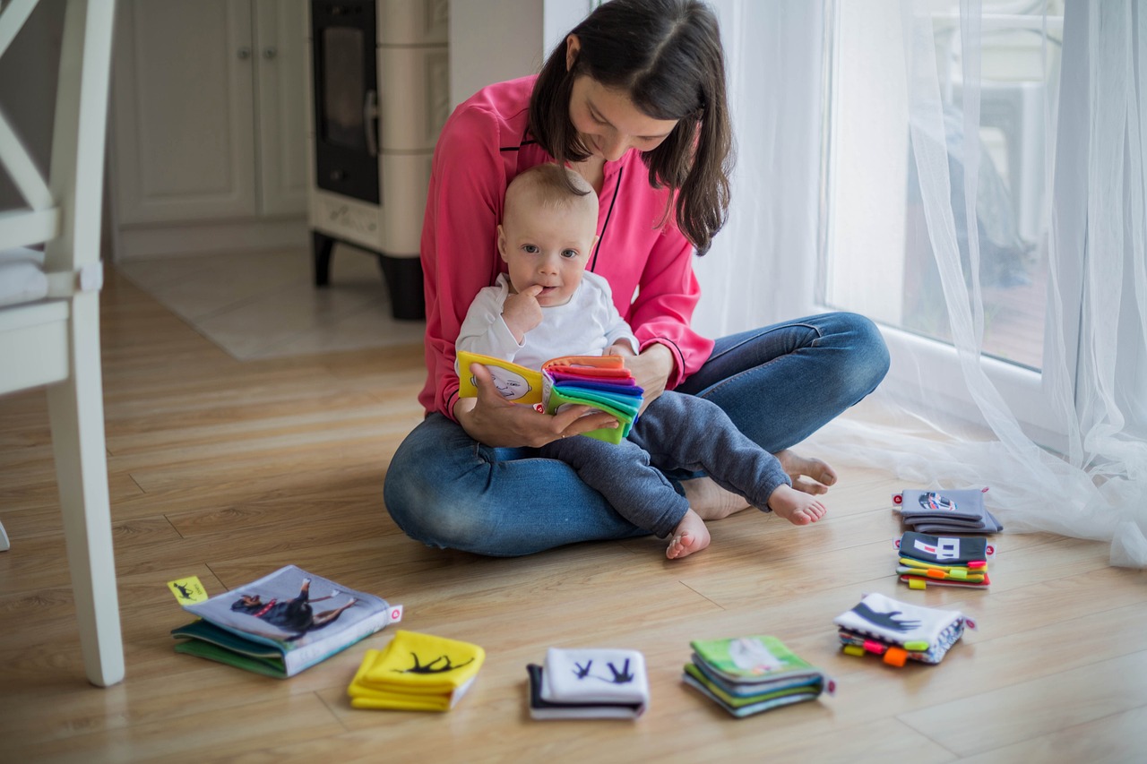 Doula in pink shirt and jeans reading to a toddler in a white shirt and jeans.