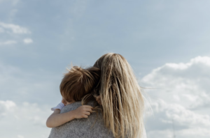 Blonde woman holding a redhead child on her shoulder