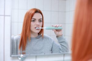 A red haired woman brushing her teeth 